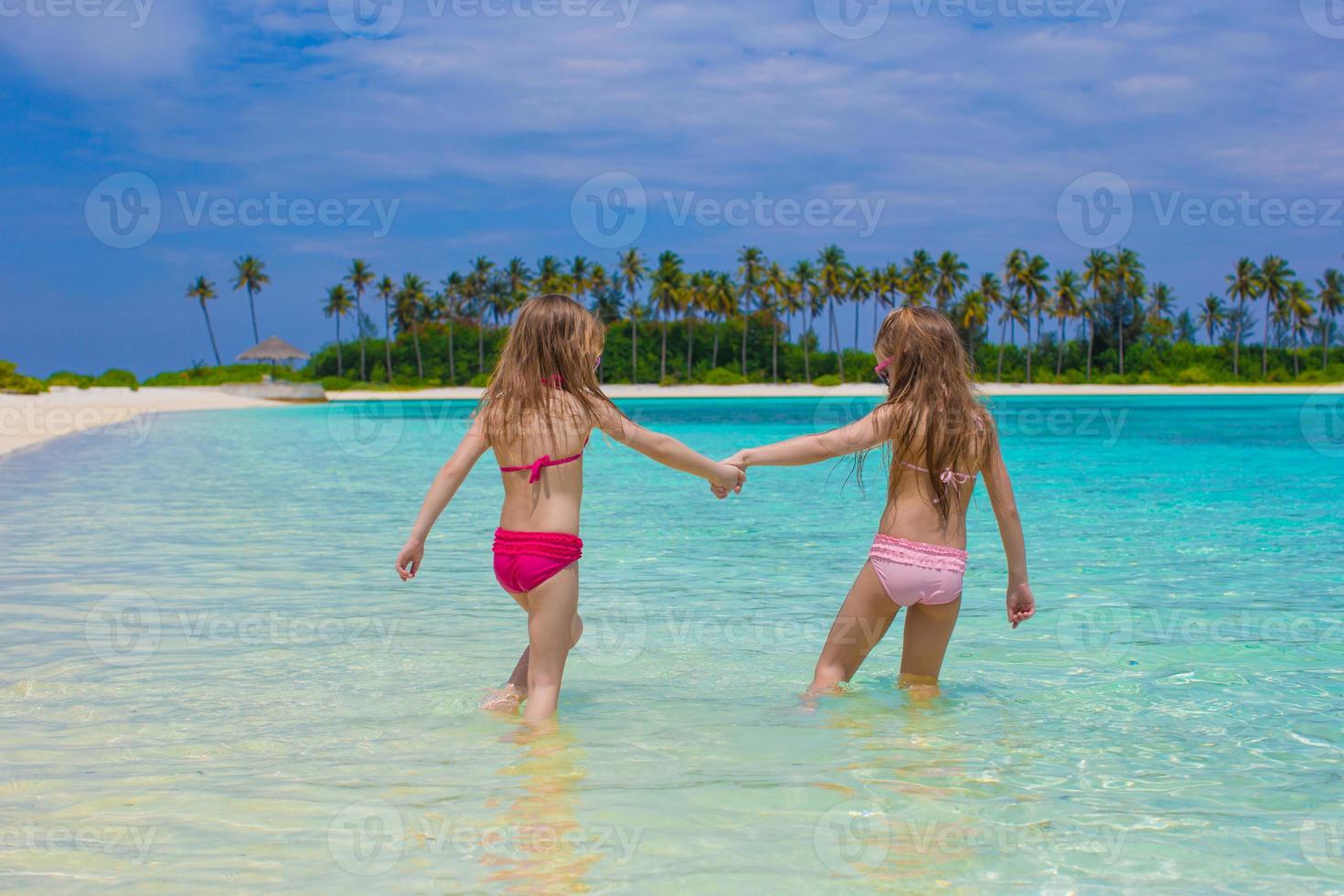 entzückende glückliche kleine mädchen haben spaß im seichten wasser im strandurlaub foto