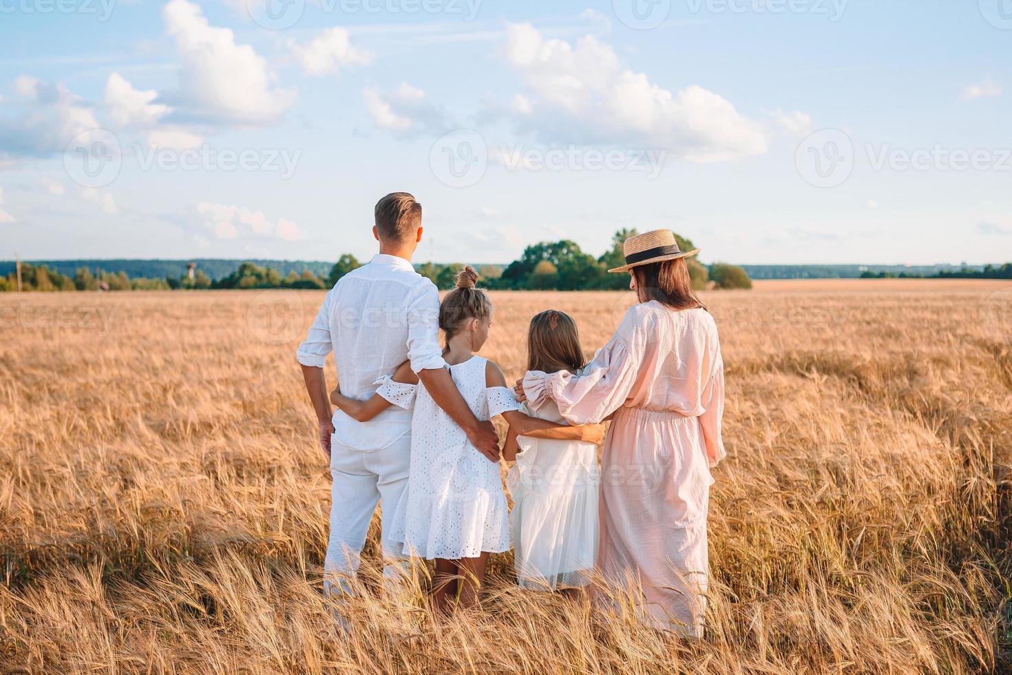 glückliche familie, die auf einem weizenfeld spielt foto