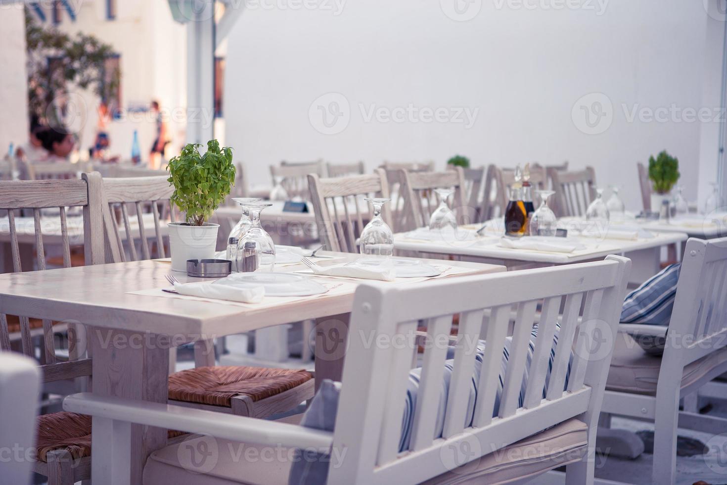 Weiße Tische mit Stühlen im leeren Open-Air-Café im Sommer foto
