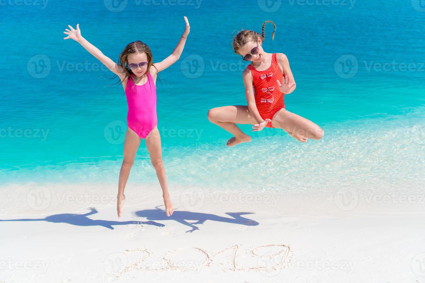 Kleine glückliche Kinder haben viel Spaß am tropischen Strand, der zusammen im seichten Wasser spielt. foto