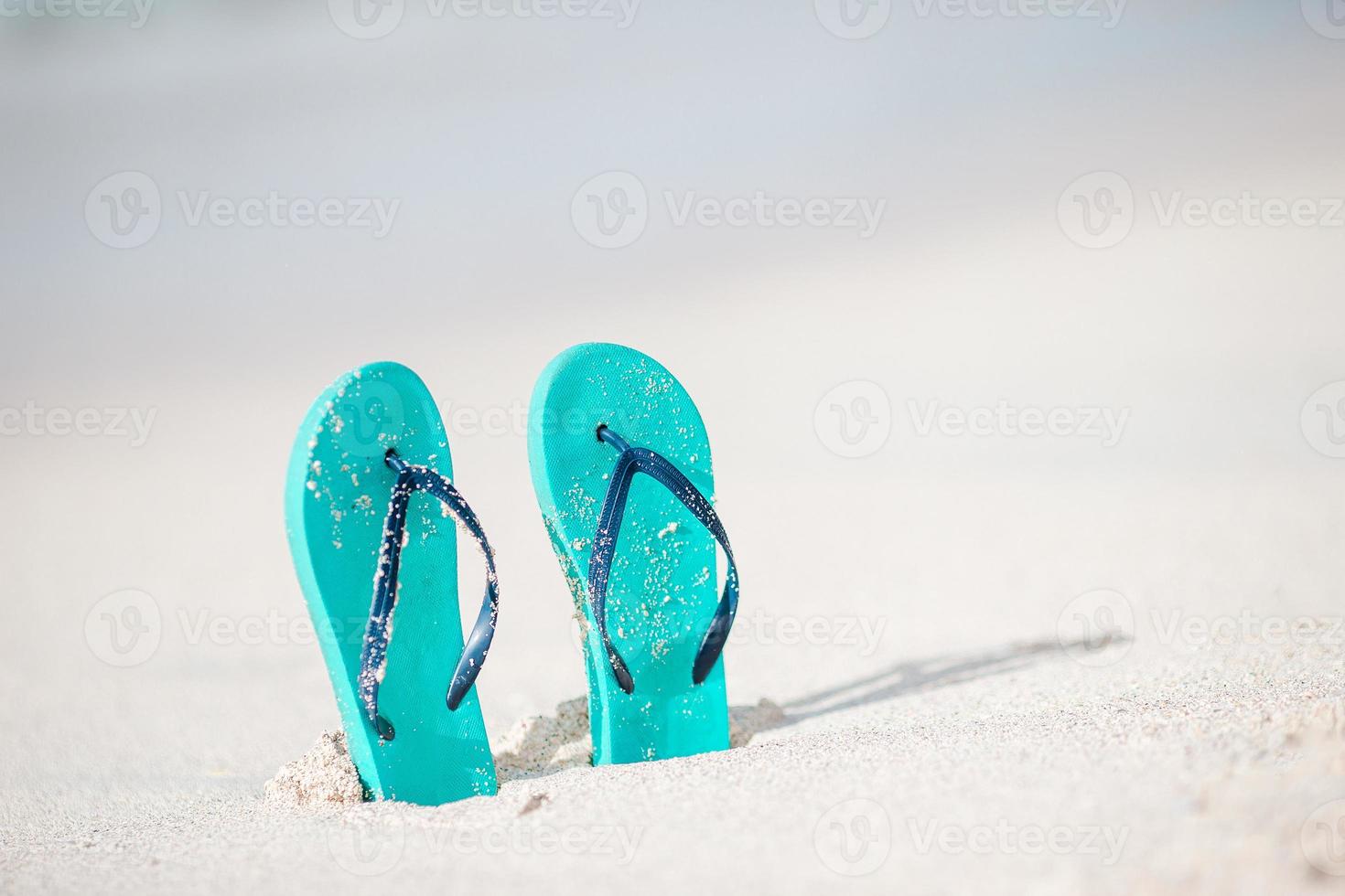 Sommerminz-Flip-Flops mit Sonnenbrille am weißen Strand foto