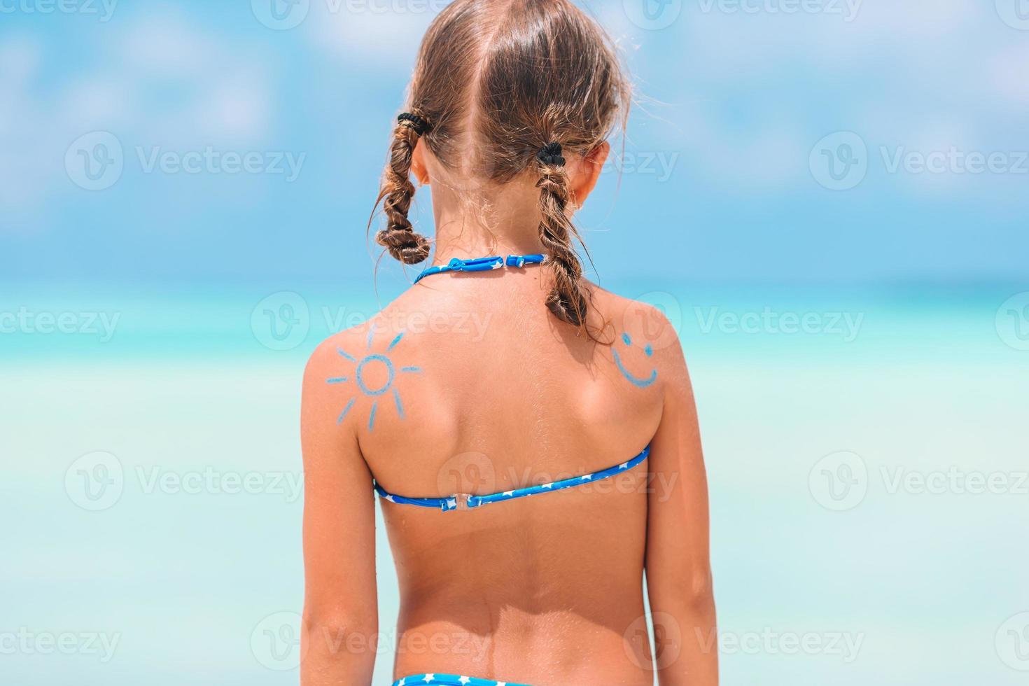 Nahaufnahme der Sonne, die mit Sonnencreme auf der Schulter des Kindes gemalt wurde foto