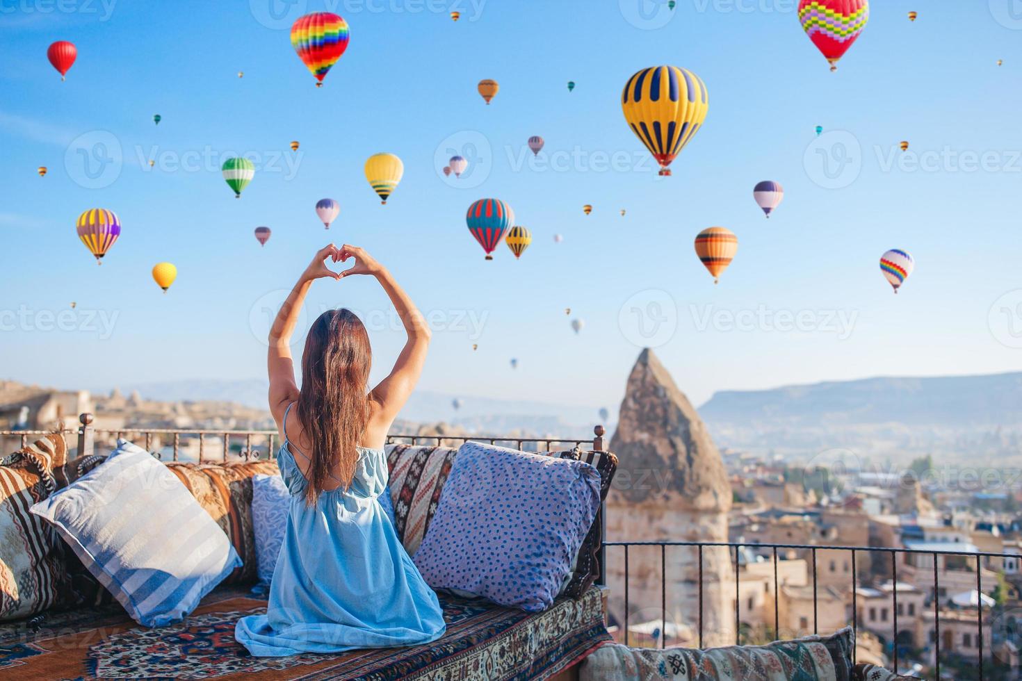 glückliche junge frau bei sonnenaufgang, die heißluftballons in kappadokien, türkei, beobachtet foto