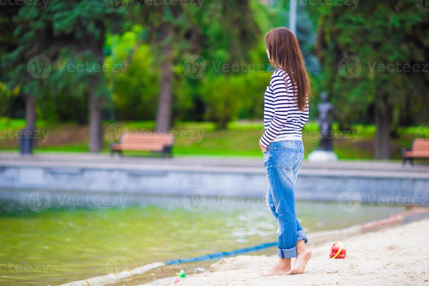 junge glückliche Frau, die an warmen Tagen in der Nähe des Sees spazieren geht foto