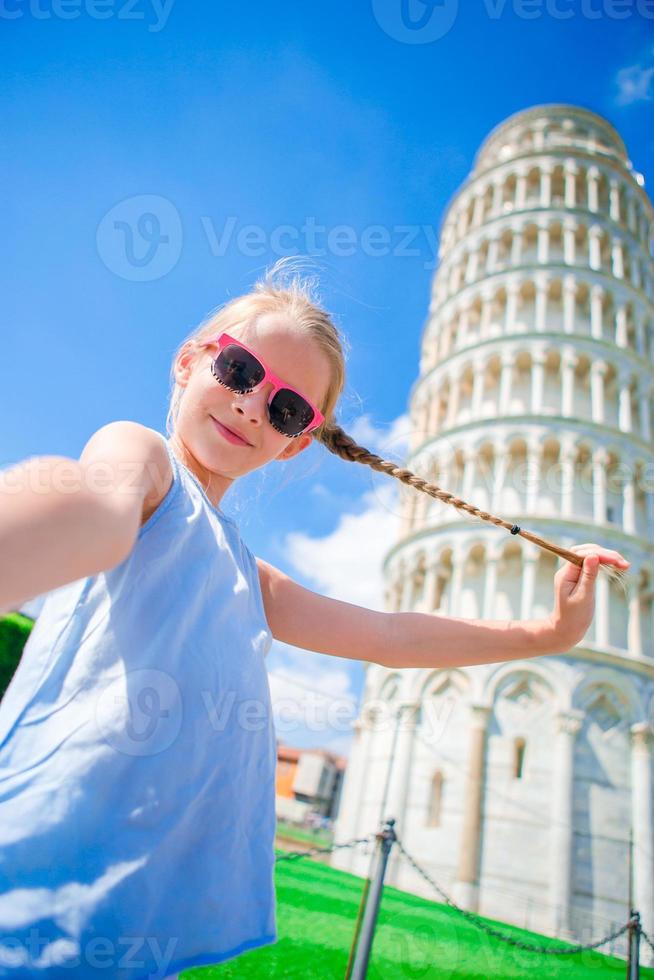 kleines mädchen, das selfie nimmt hintergrund der schiefe turm in pisa, italien foto