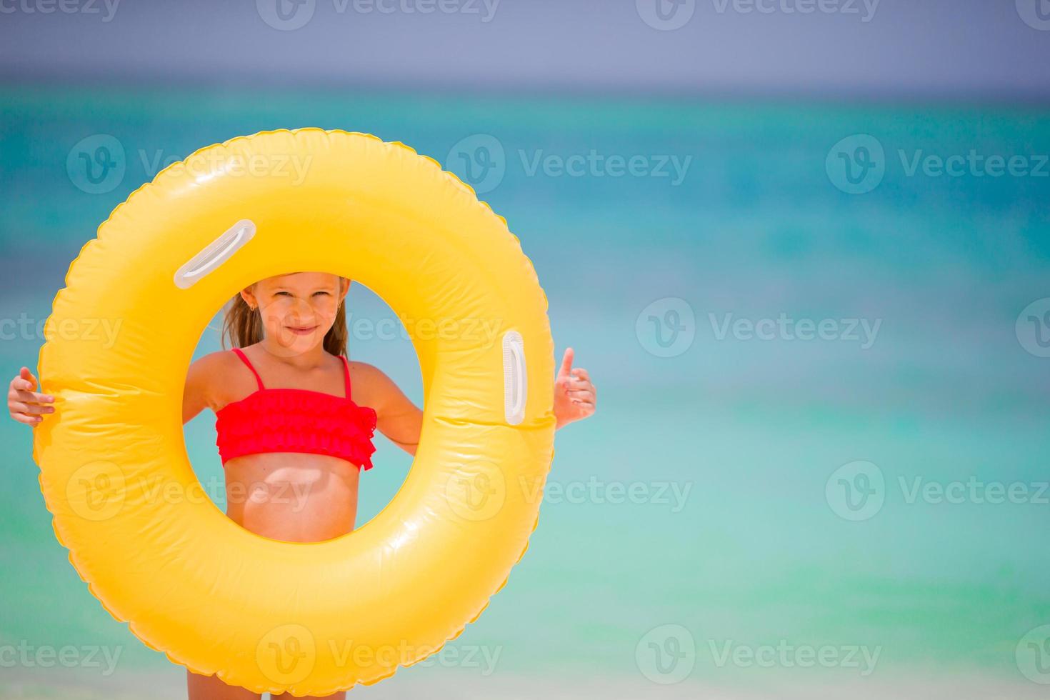 Entzückendes Mädchen mit aufblasbarem Gummikreis am weißen Strand foto