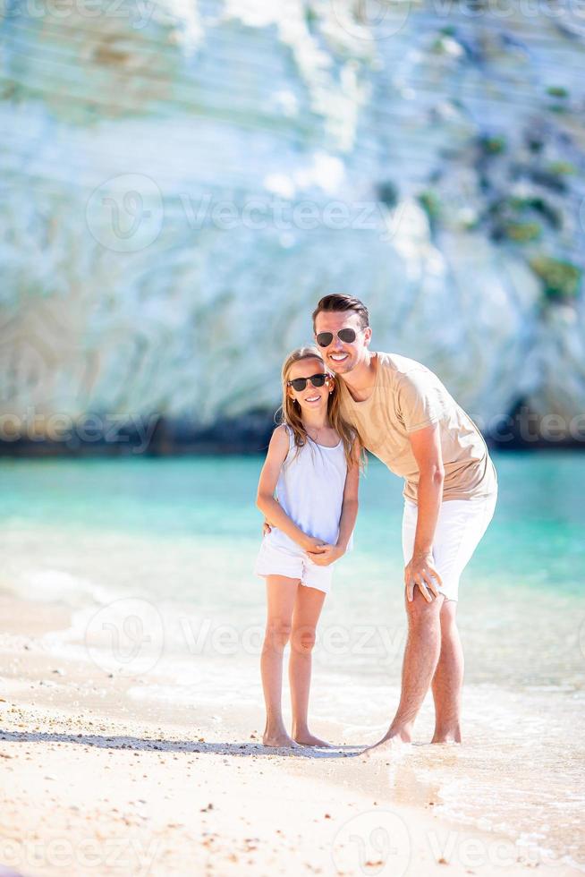 Glücklicher Vater und seine entzückende kleine Tochter am tropischen Strand haben Spaß foto