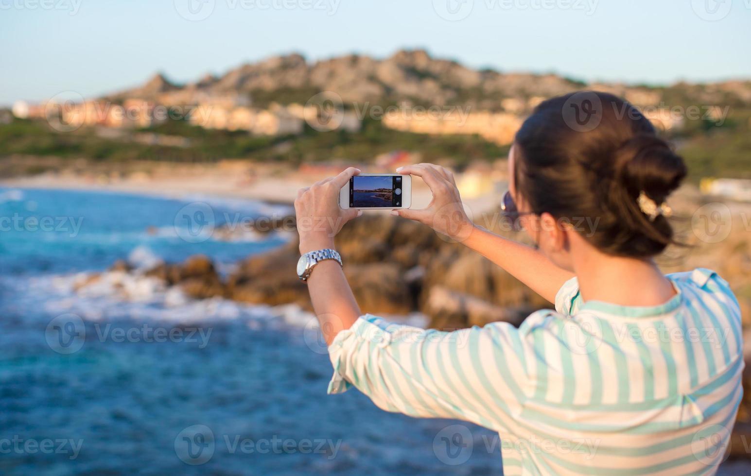 junge Frau macht während des Strandurlaubs ein Foto am Telefon