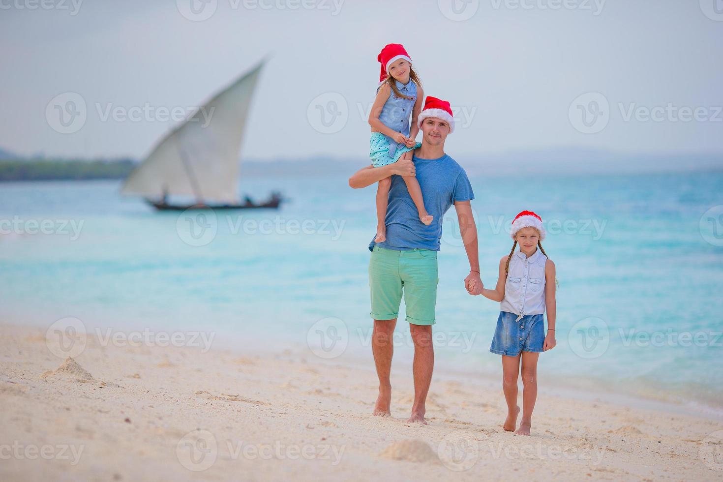 glückliche familie in weihnachtsmützen im sommerurlaub. weihnachtsferien mit einer jungen vierköpfigen familie, die ihre seereise genießt foto