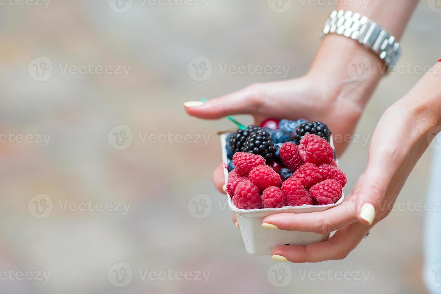 Beerenfrüchte in weiblichen Händen hautnah. Heidelbeeren, Himbeeren, Erdbeeren und Brombeeren auf dem Markt. foto