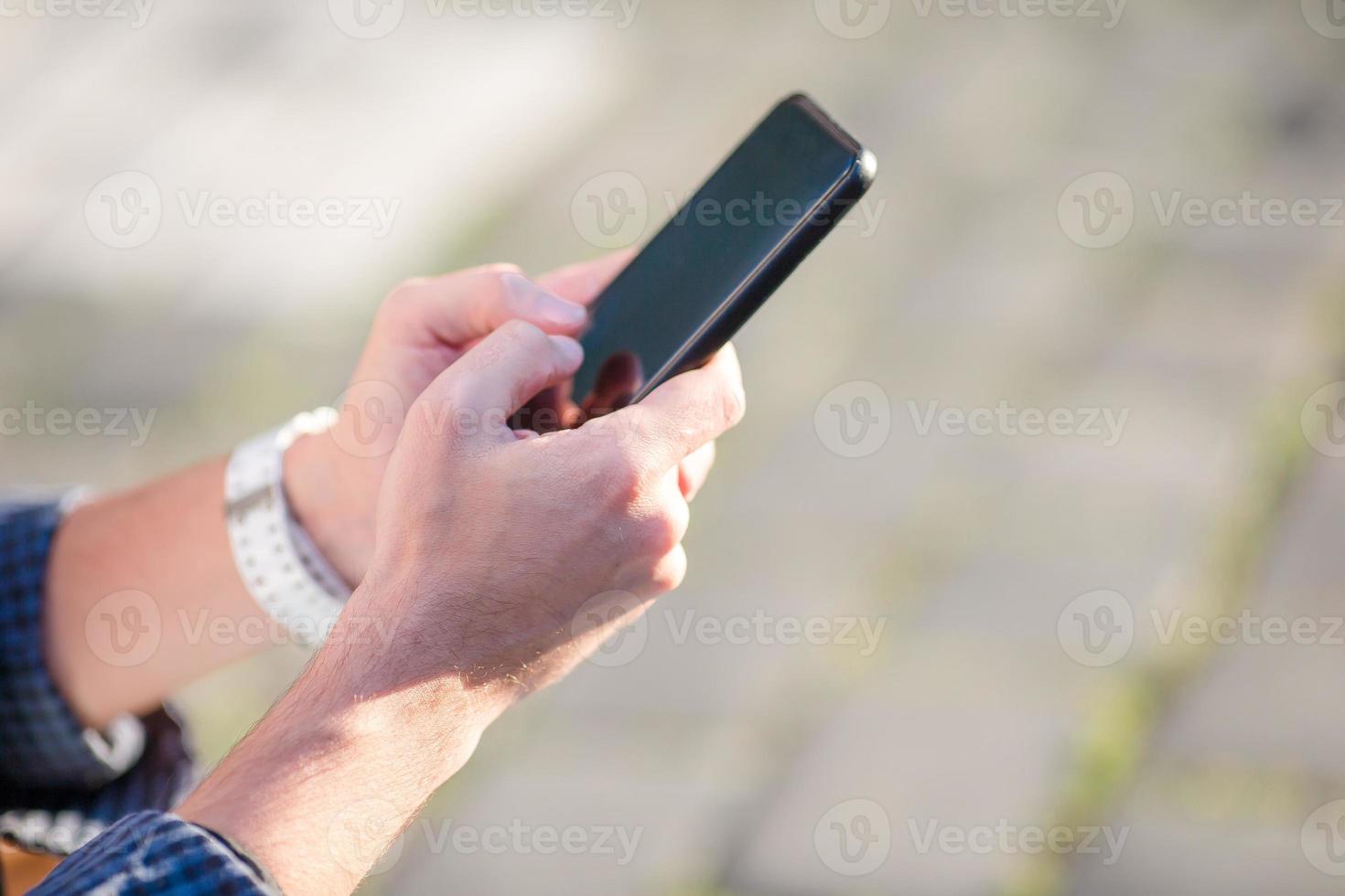 Nahaufnahme männlicher Hände hält Handy im Freien auf der Straße. mann, der mobiles smartphone verwendet. foto