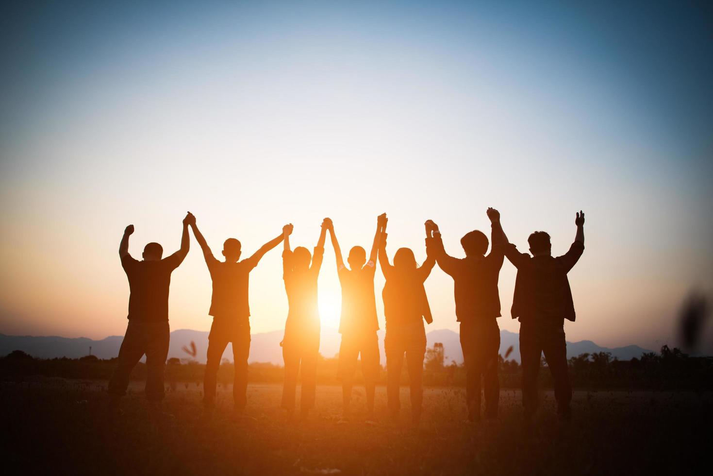 Silhouette des glücklichen Teams, das Hände in der Luft verbindet foto