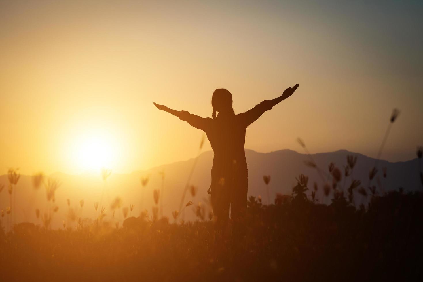 Silhouette einer Frau, die über einem schönen Himmelhintergrund betet foto