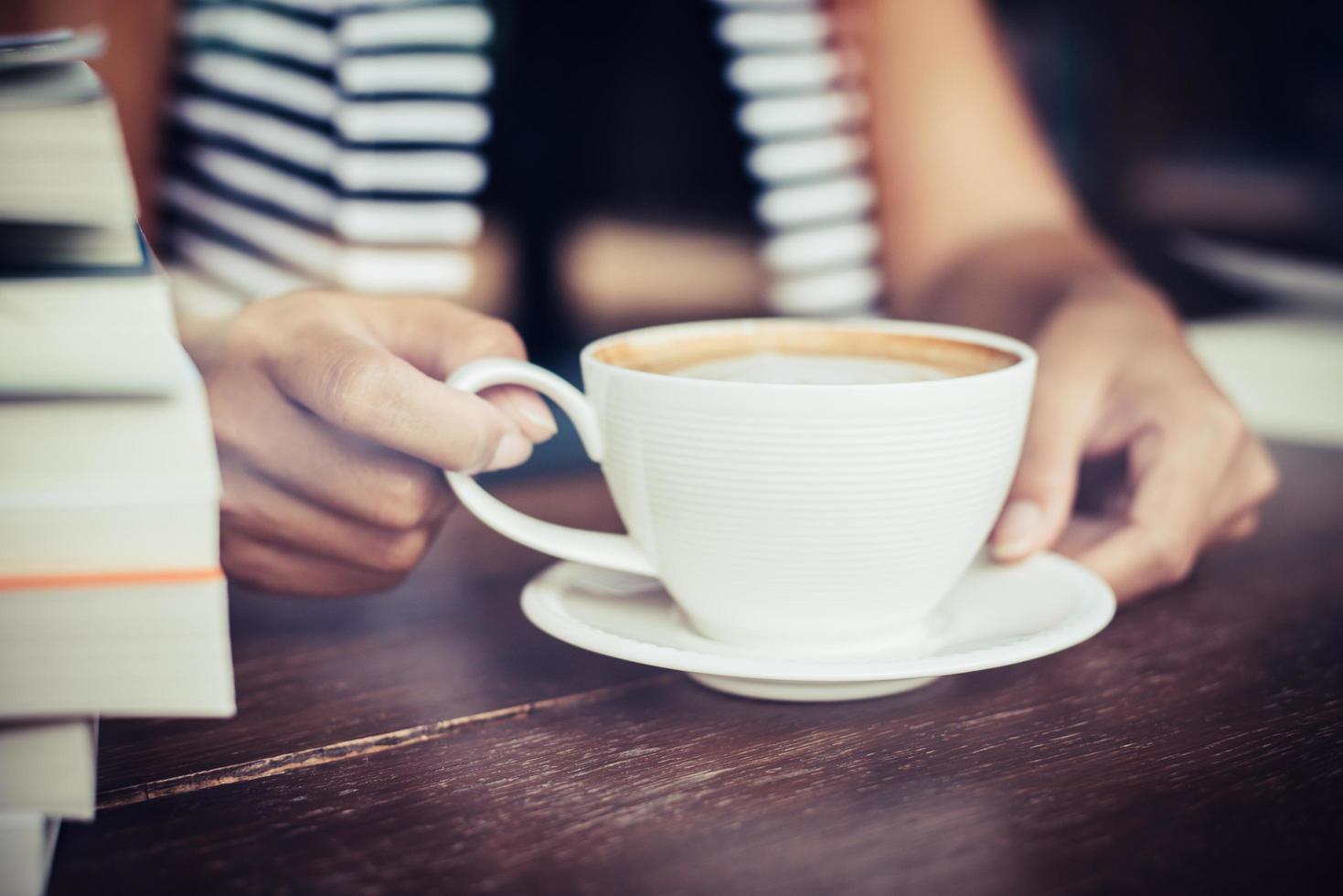 Frauenhände, die mit Kaffee im Café entspannen foto