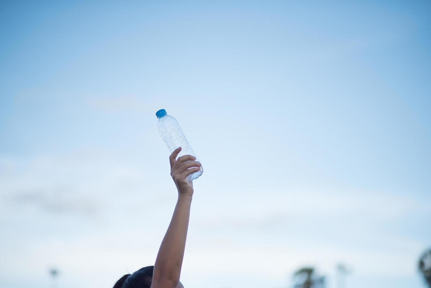 Frauenhand hält eine Plastikwasserflasche foto