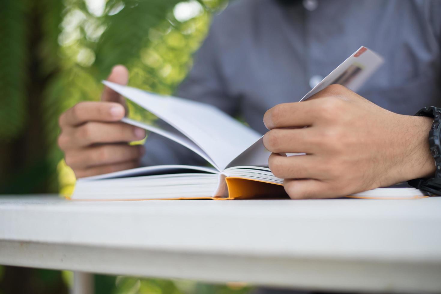 junger Mann, der Bücher im Hausgarten mit Natur liest foto