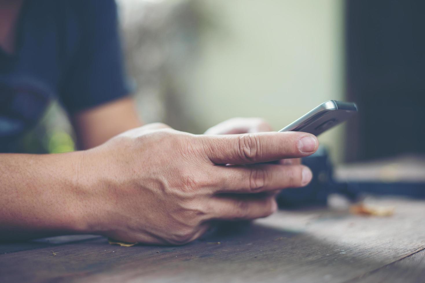 Person, die Smartphone an einem Tisch hält foto