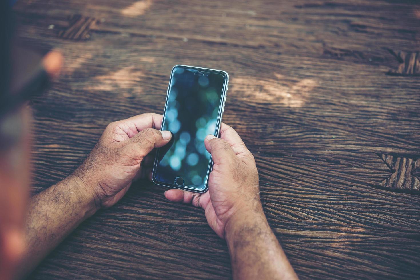 Person, die Smartphone an einem Tisch hält foto