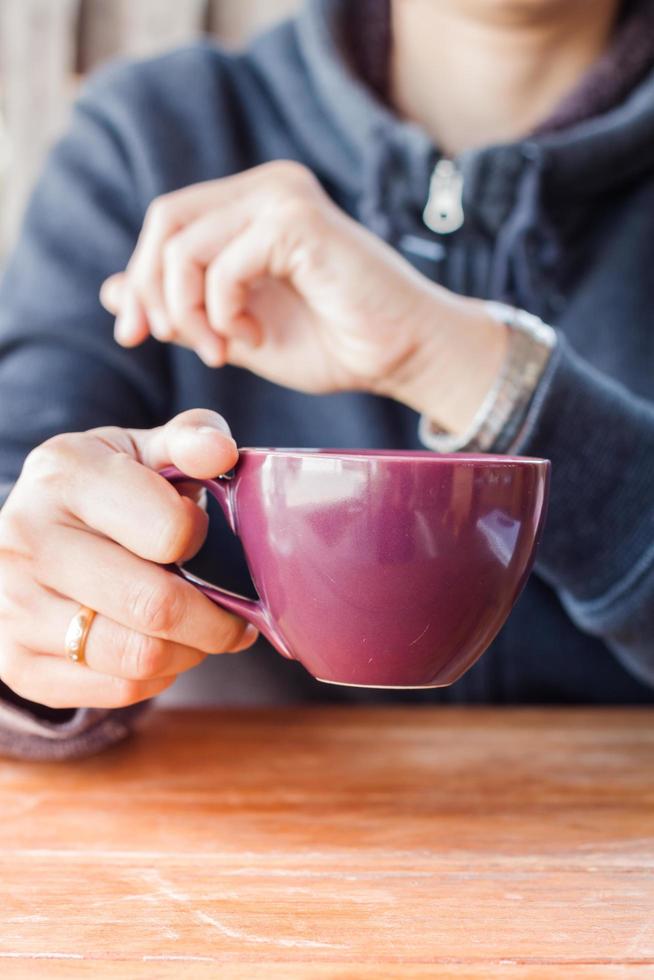 Person, die eine lila Kaffeetasse hält foto