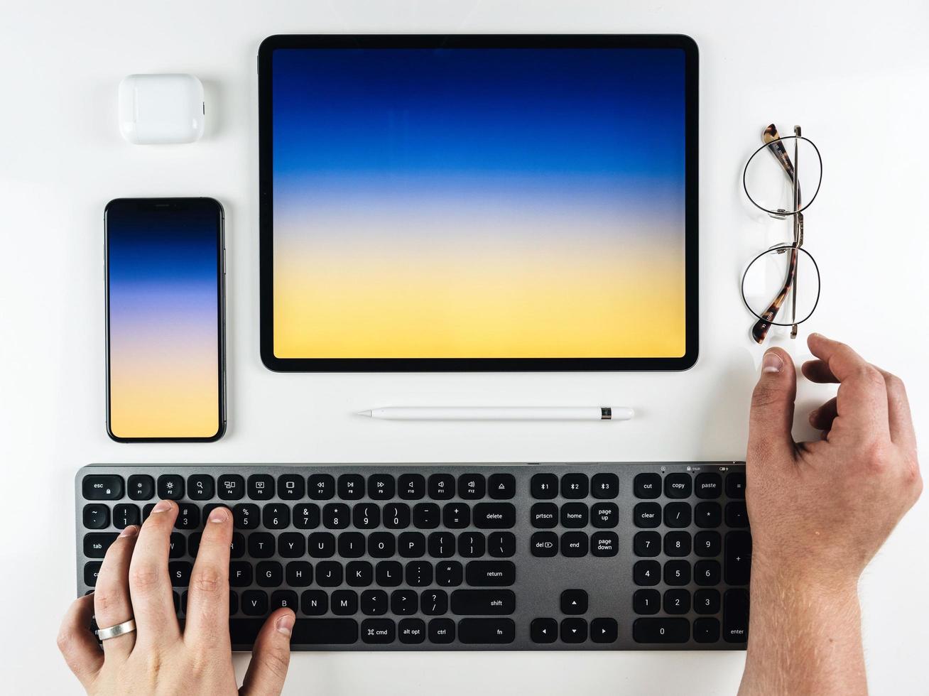 Draufsicht der Hände auf einer Tastatur mit einem Tablett und einem Telefon foto