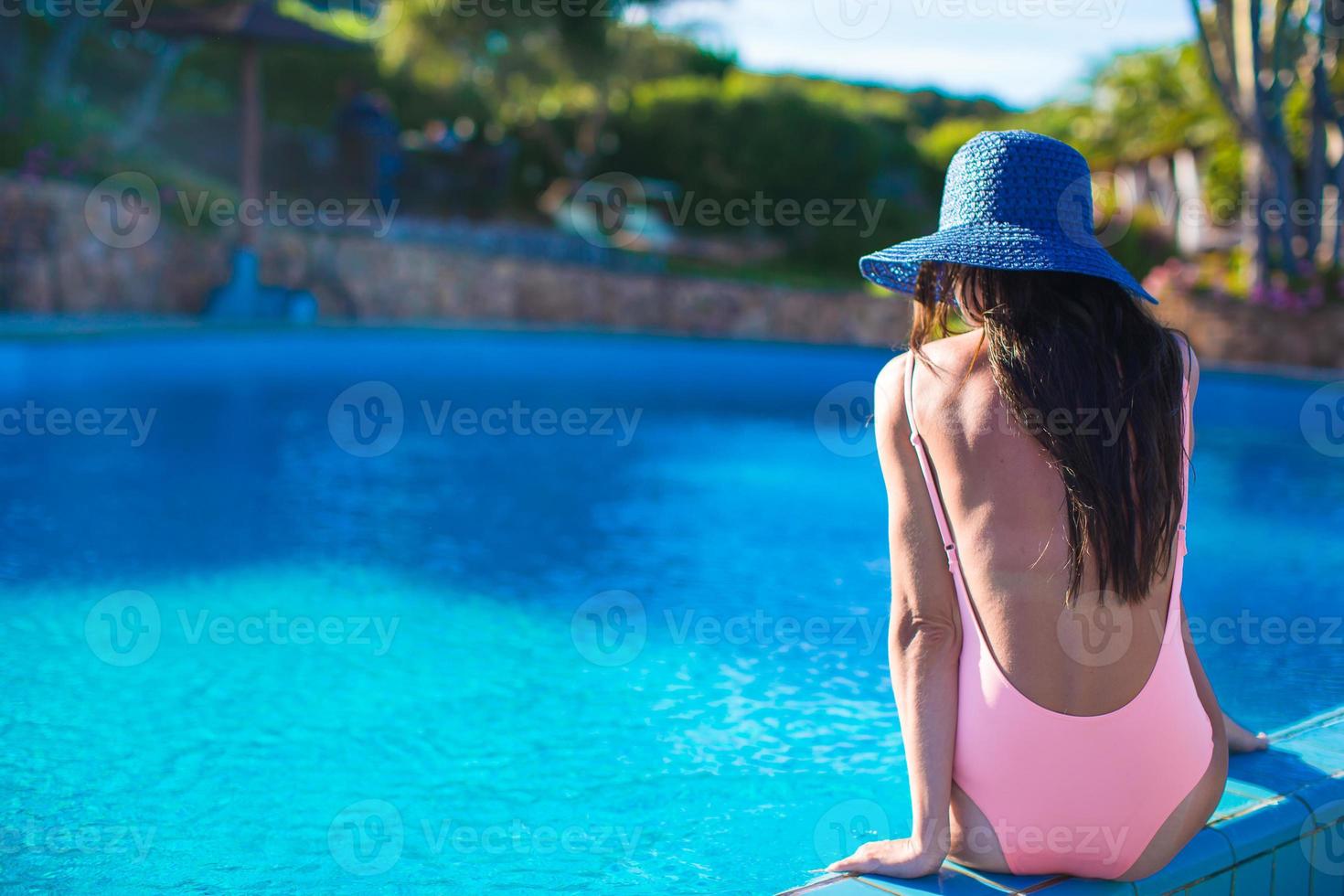 schönes junges mädchen, das nahe dem schwimmbad sich entspannt foto