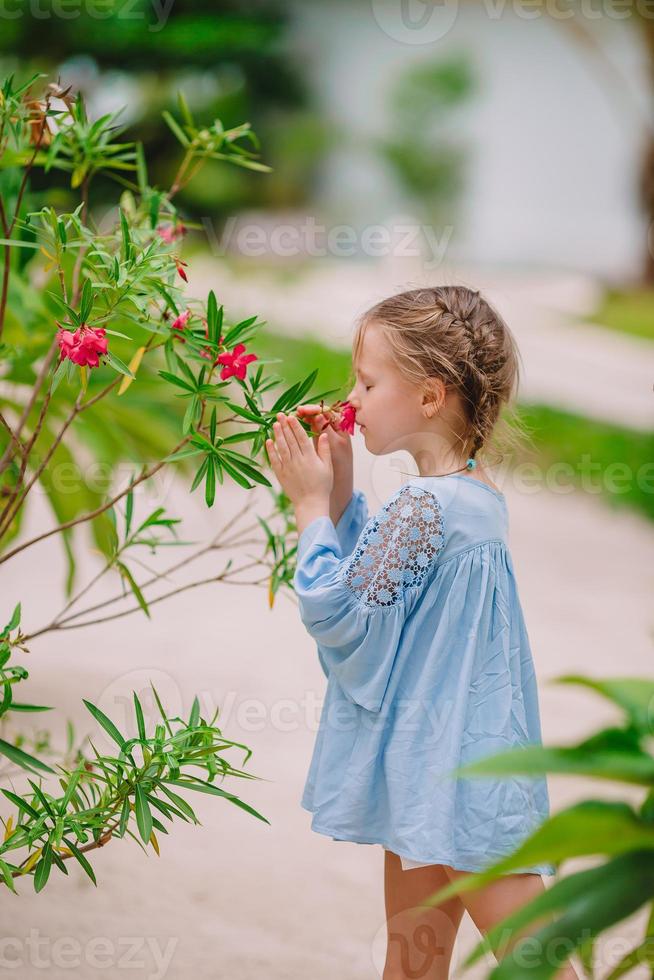 Kleines entzückendes Mädchen, das am Sommertag bunte Blumen riecht foto