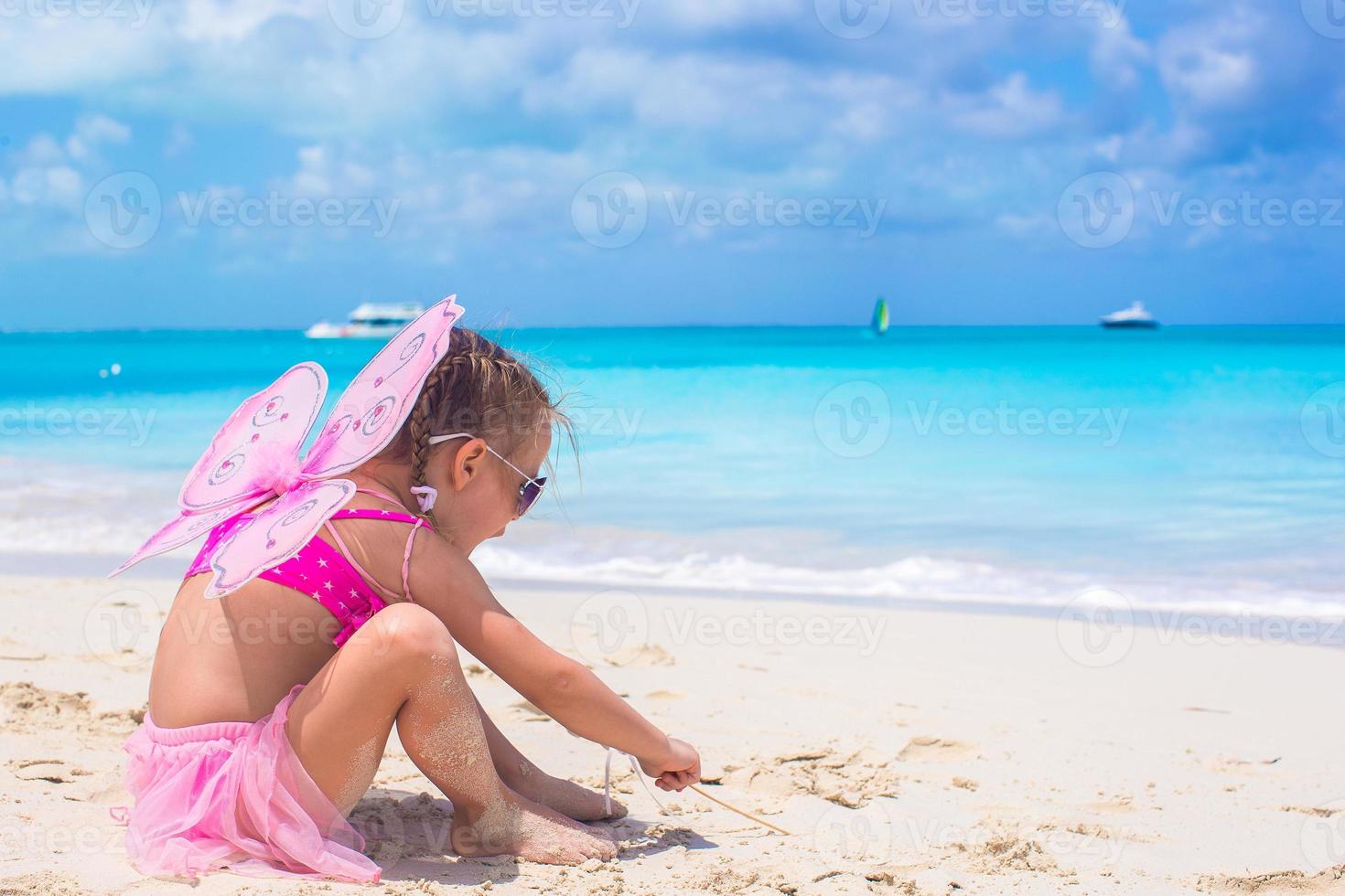 entzückendes kleines mädchen mit flügeln wie schmetterling im strandurlaub foto