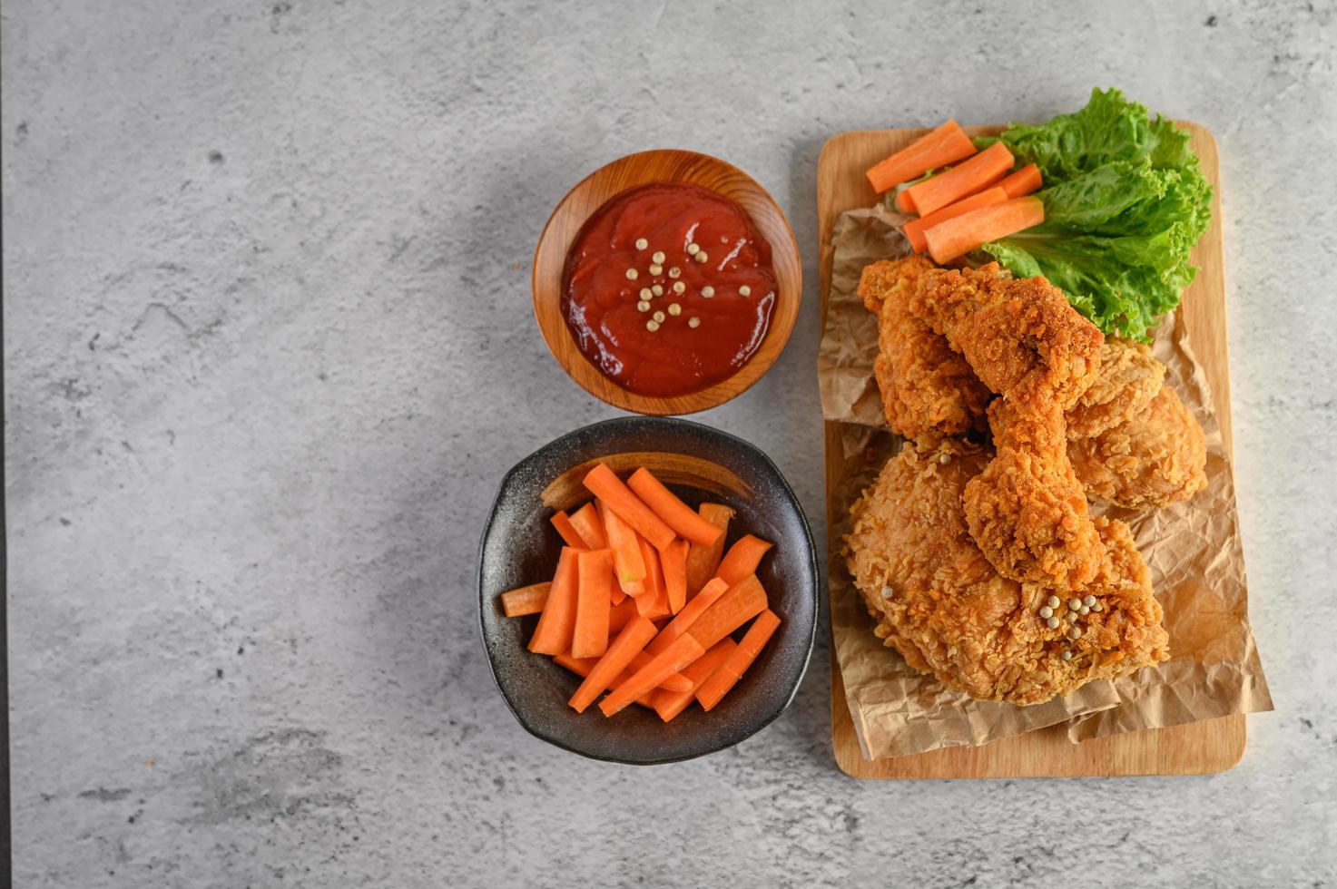 knusprig gebratenes Hähnchen und Karottenstangen mit Sauce foto