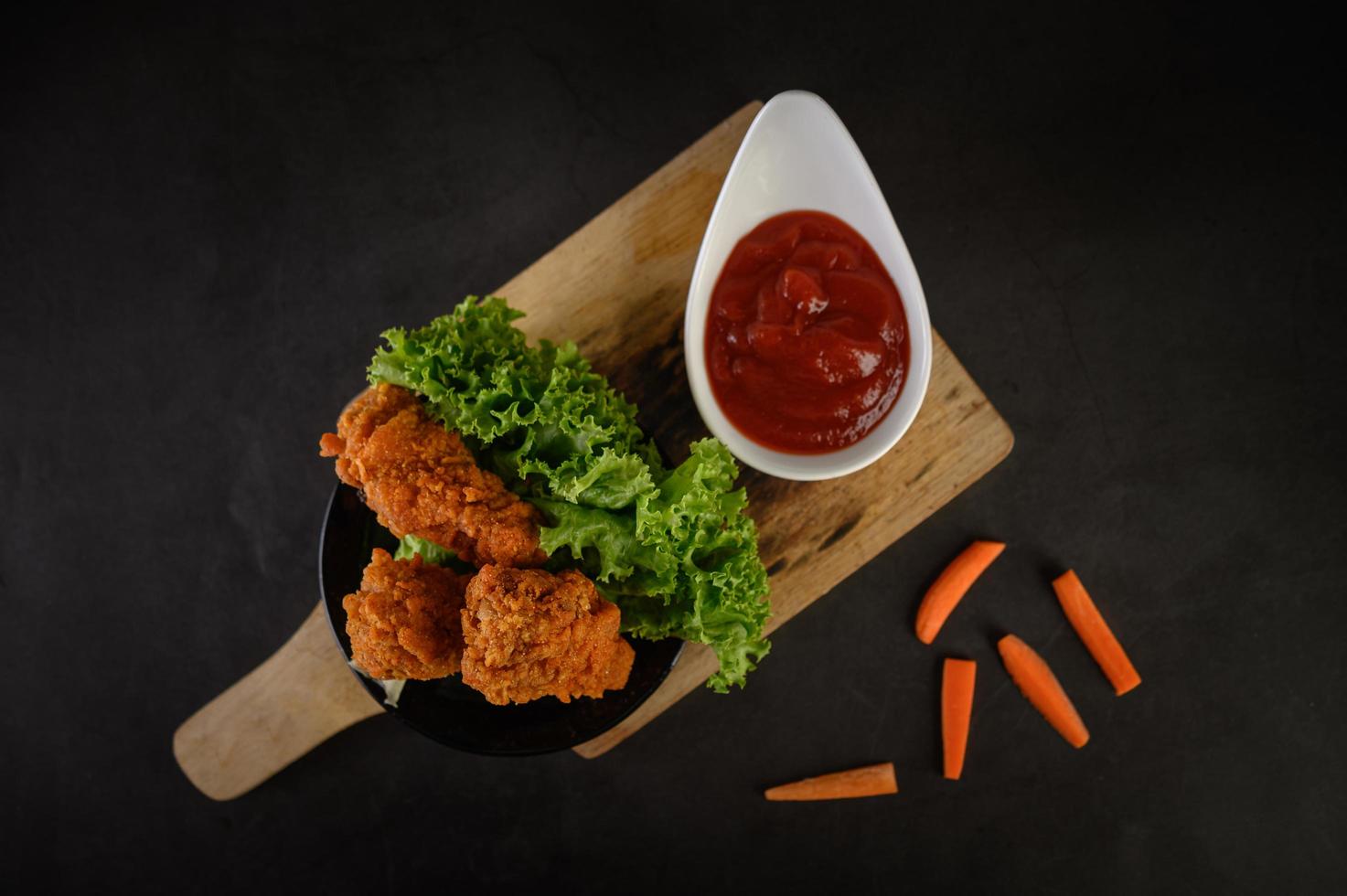 knusprig gebratenes Hähnchen und Karottenstangen mit Sauce foto