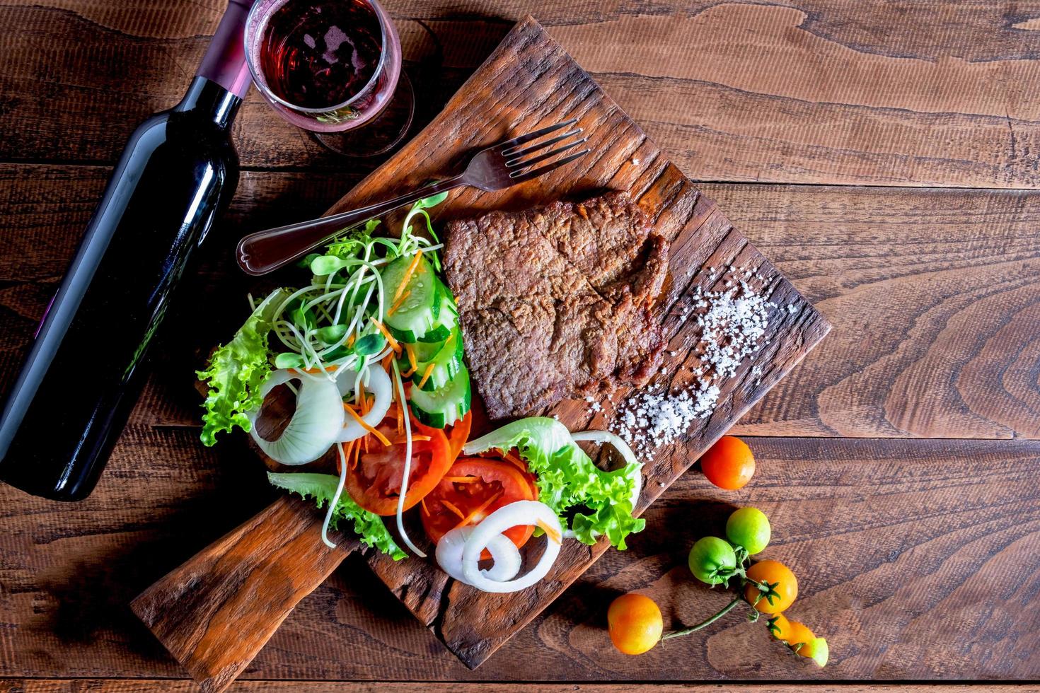 Steak und Salat auf einem Holzschneidebrett foto