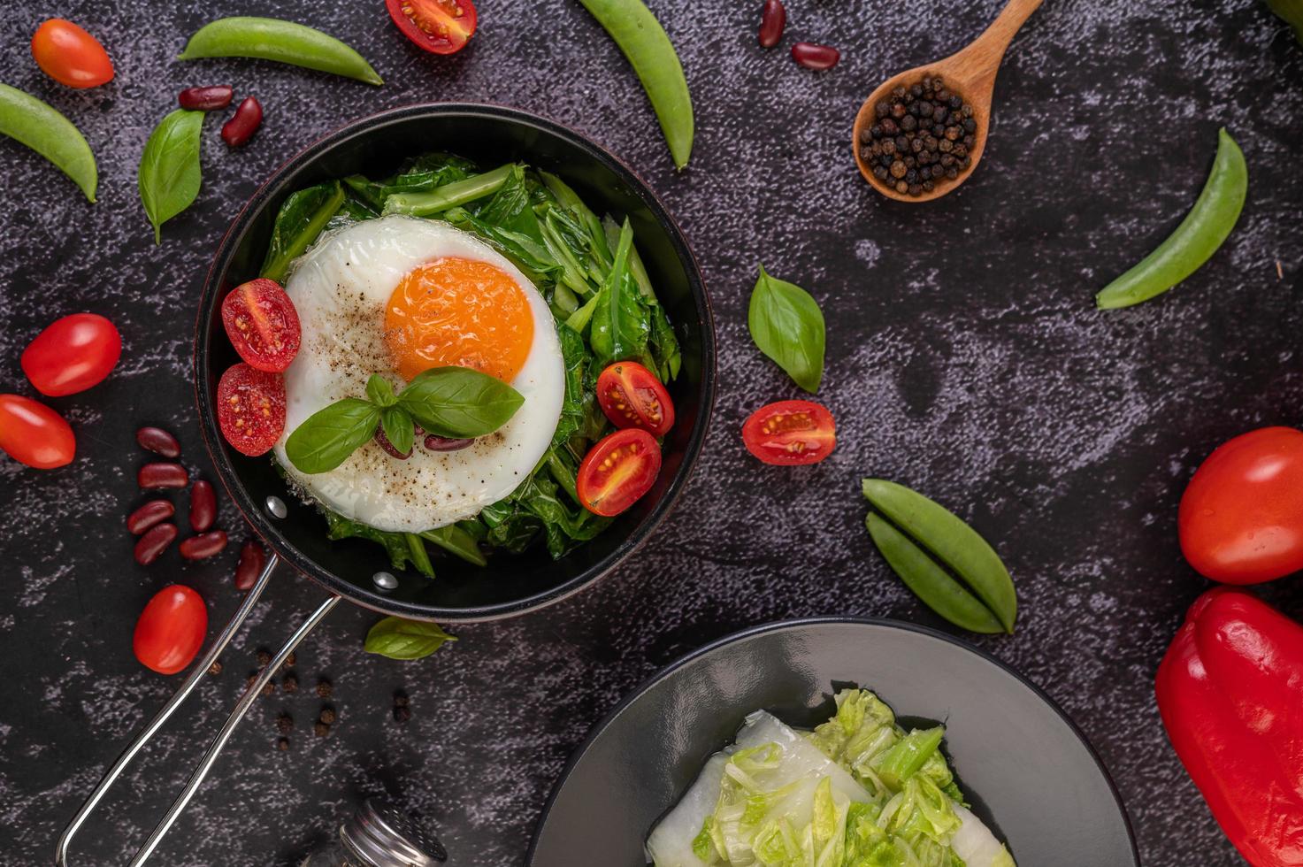 Grünkohl in einer Pfanne mit Ei und Tomaten umrühren foto