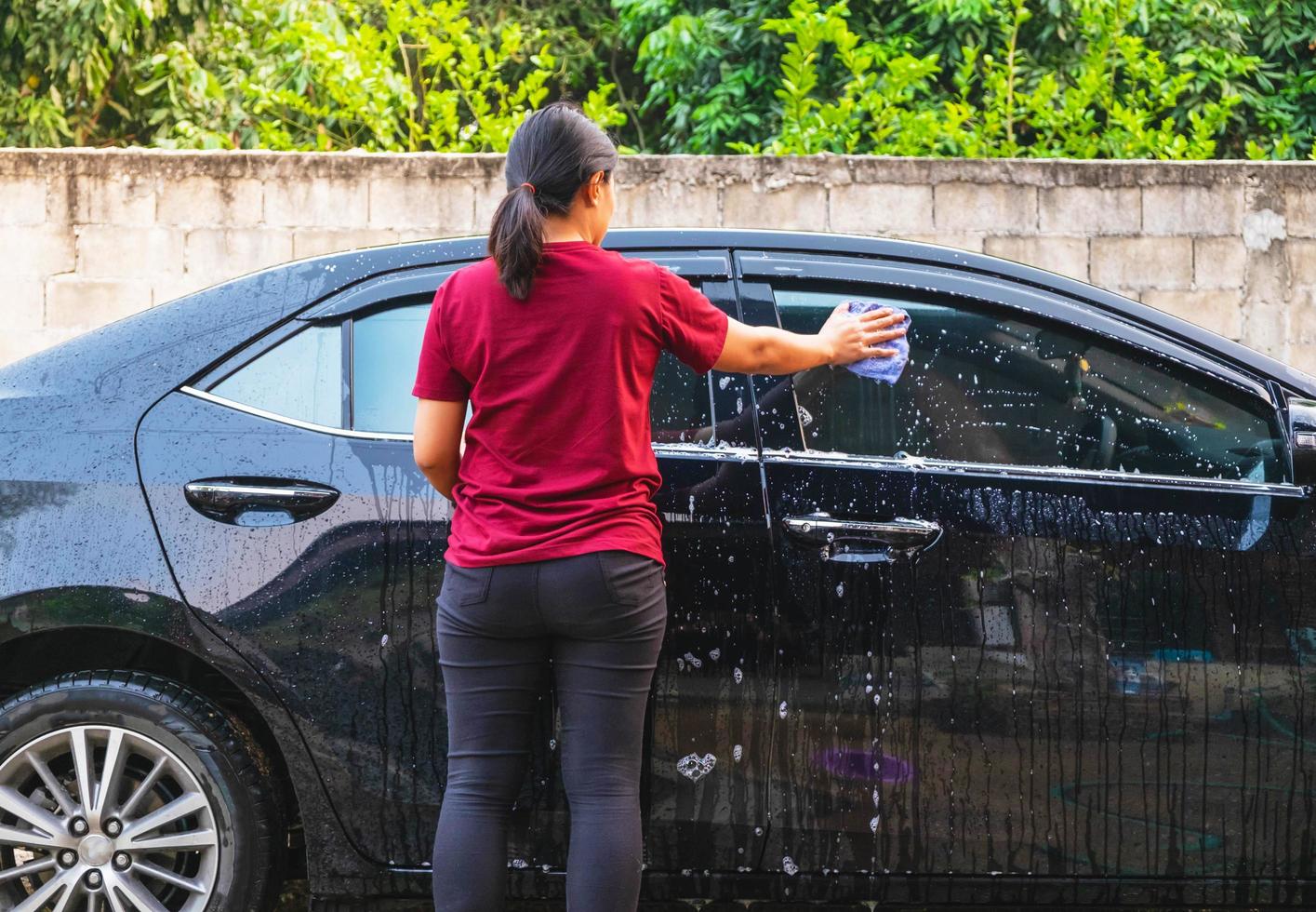 Frau, die tagsüber ein Auto wäscht foto