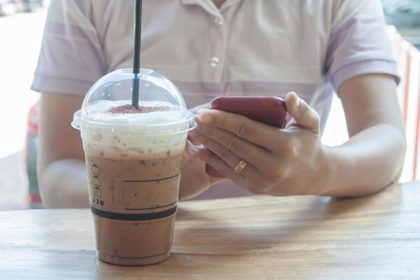 Person, die ein Telefon mit einer Frappe hält foto