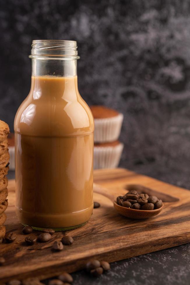 Kaffee in der Flasche mit Kaffeebohnen und Muffins foto