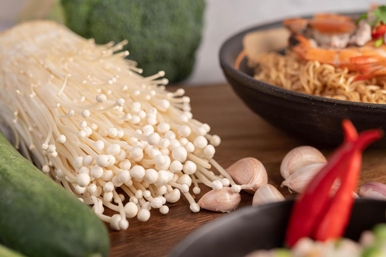 goldener Nadelpilz, Papaya, Knoblauch und Chili auf einem Holztisch foto