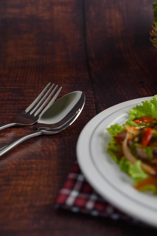 rostfreier Löffel und Gabel und würziger Salat foto