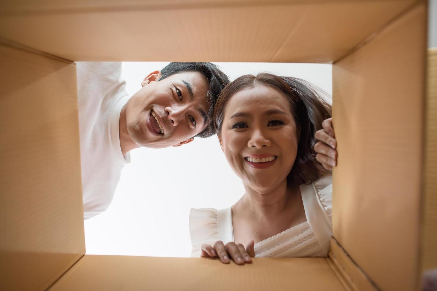 glückliches Paar, das eine Schachtel öffnet und hineinschaut foto