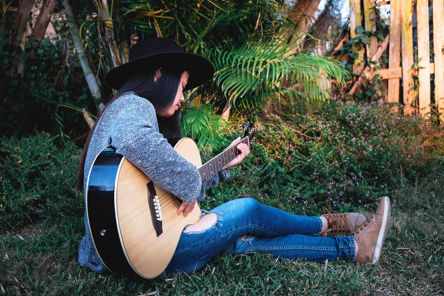 Frau sitzt im Gras und spielt Gitarre foto