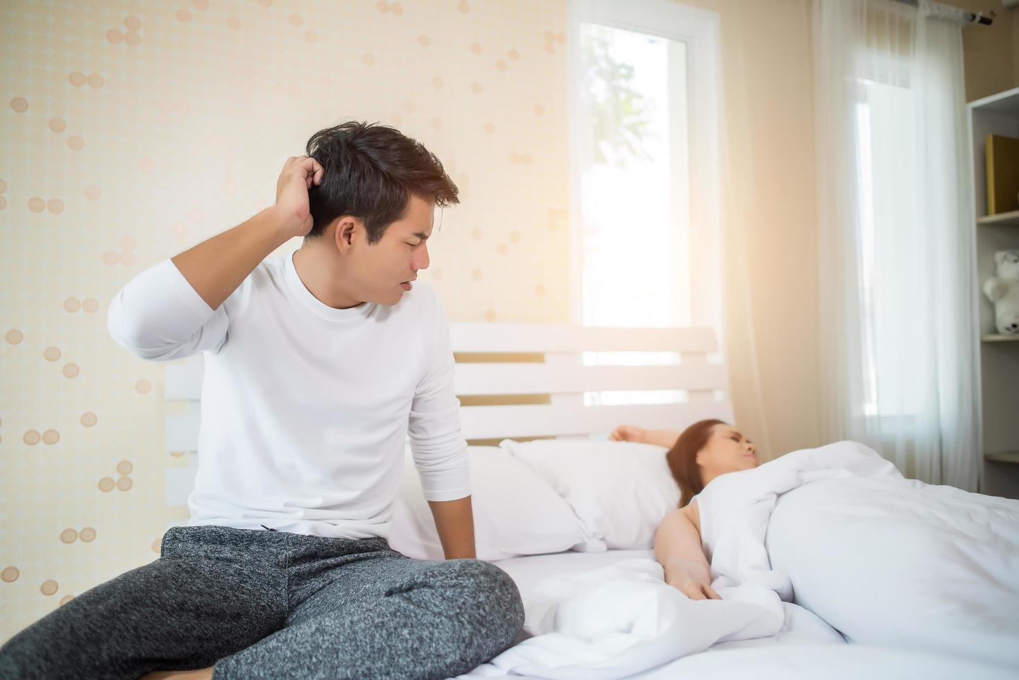 verärgerter Mann auf dem Bett, nachdem er mit seiner Freundin gestritten hatte foto