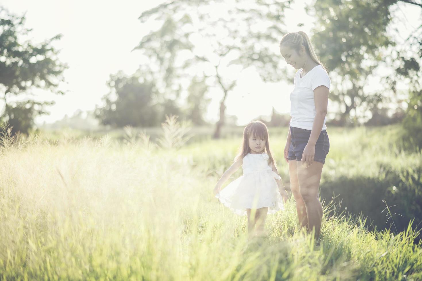 Mutter und kleine Tochter spielen auf einem Feld im Sonnenlicht foto