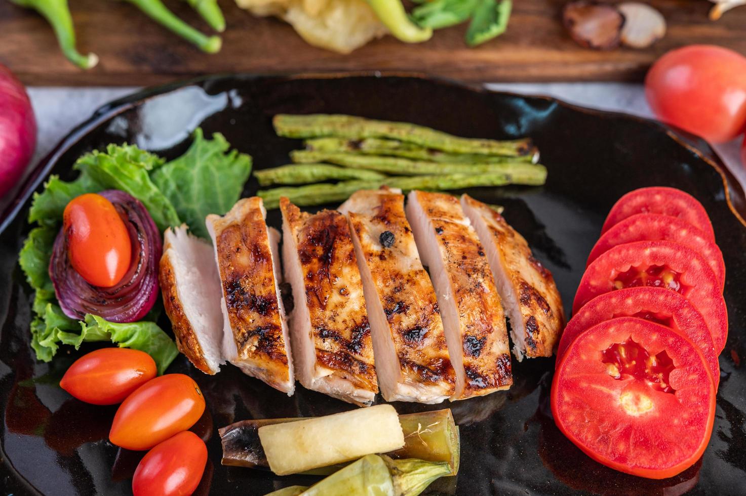 Hühnchensteak mit Salatgemüse auf einem schwarzen Teller foto