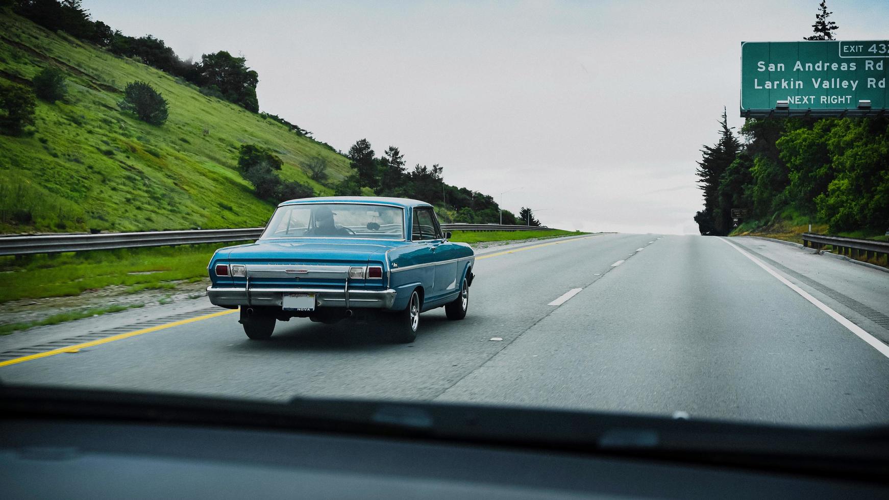 altes blaues Auto, das auf der kalifornischen Autobahn fährt foto