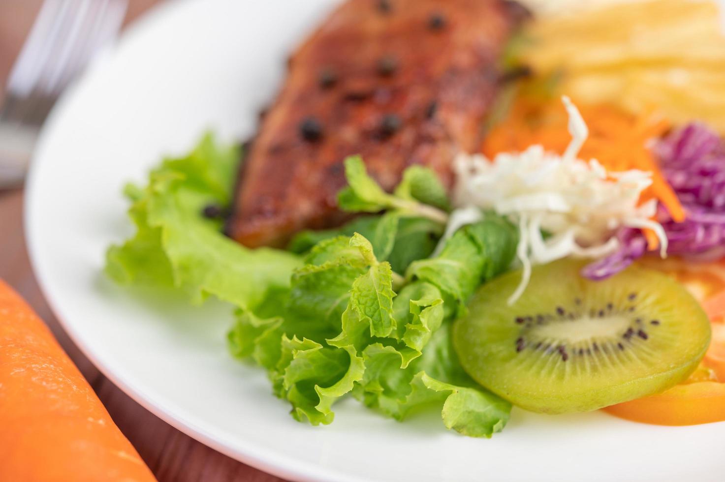 Fischsteak mit Pommes Frites, Obst und Gemüse foto