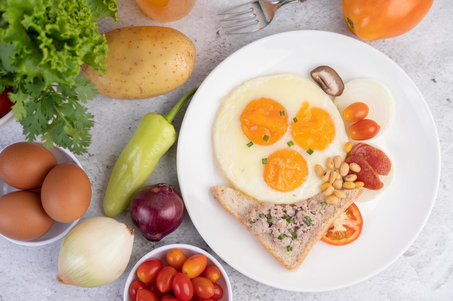 Spiegeleier, Wurst, gehacktes Schweinefleisch, Brot und rote Bohnen foto