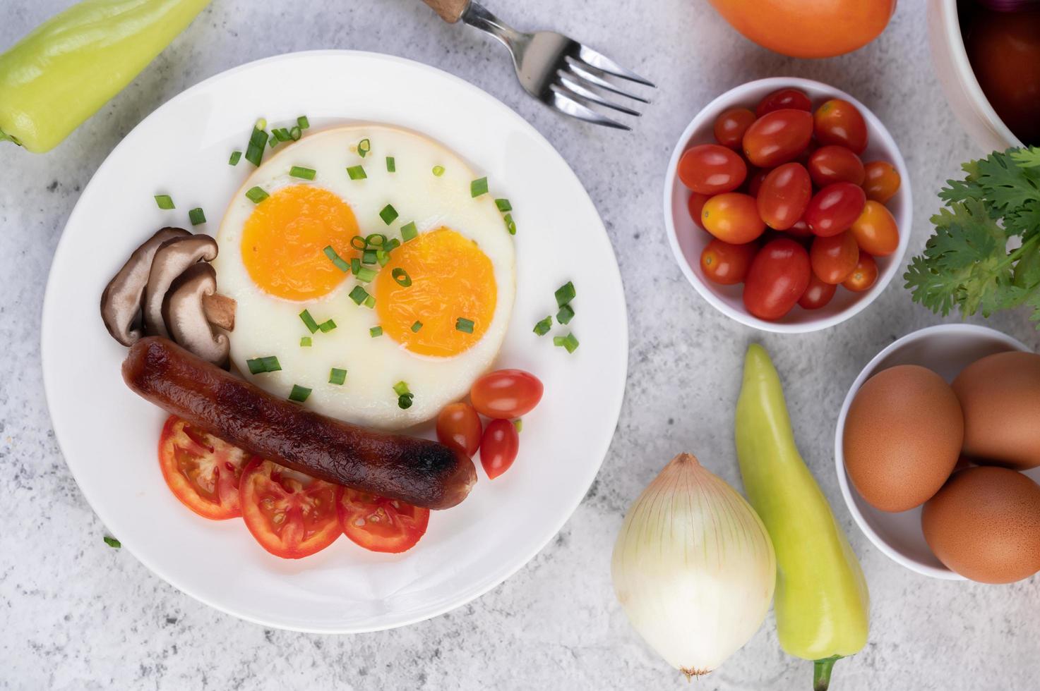 Frühstücksteller mit Spiegeleiern, Tomaten, chinesischer Wurst und Pilzen foto