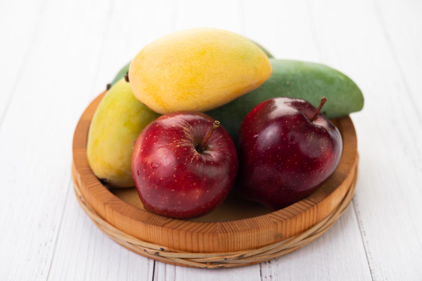 Äpfel und Mangos in einer Holzschale foto