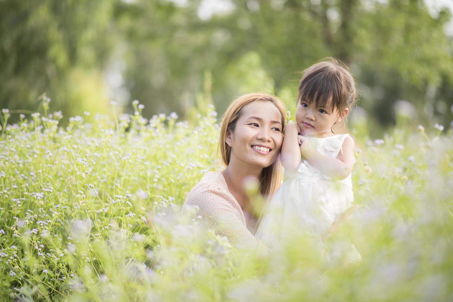 Mutter und kleine Tochter spielen zusammen auf einer Wiese foto