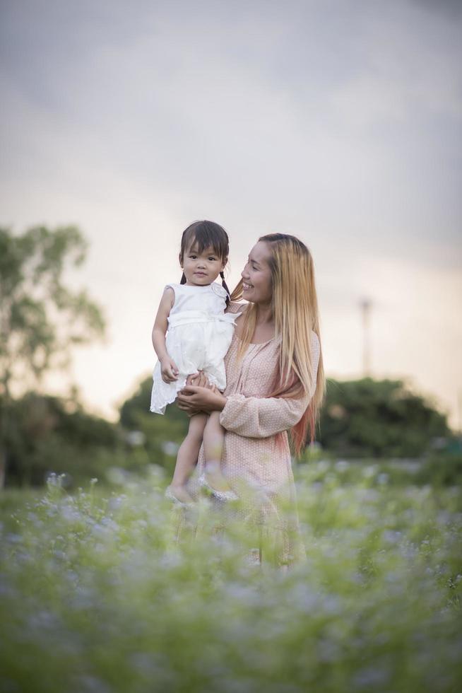 Mutter und kleine Tochter spielen zusammen auf einer Wiese foto