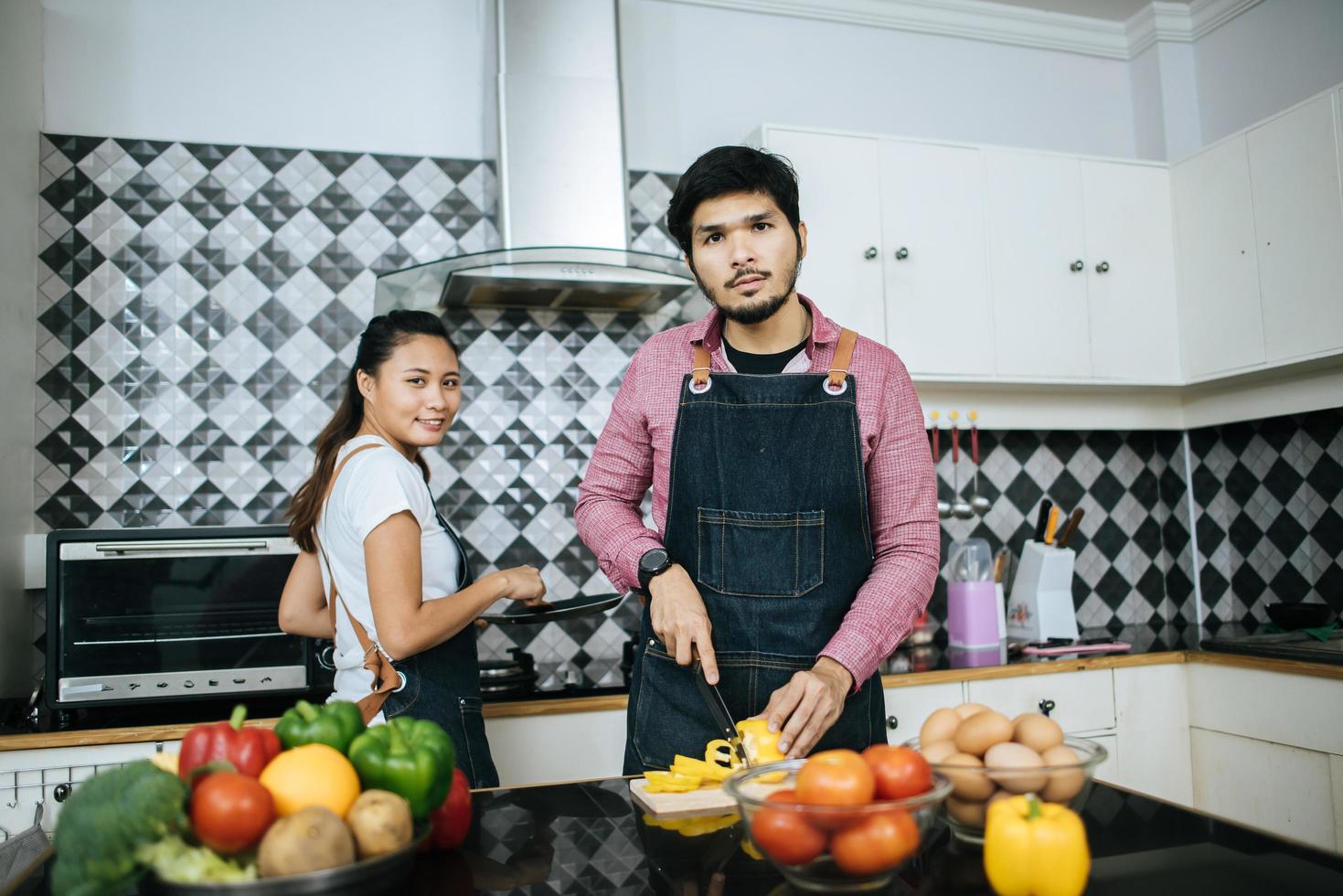 glückliches lächelndes junges Paar, das zusammen in der Küche kocht foto