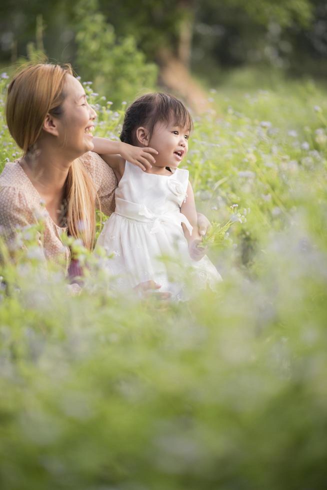 Mutter und kleine Tochter spielen zusammen auf einer Wiese foto